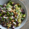 A white bowl of carrot and cucumber salad with feta, chickpeas, and cilantro. Not easy to see is the maple tahini dressing.