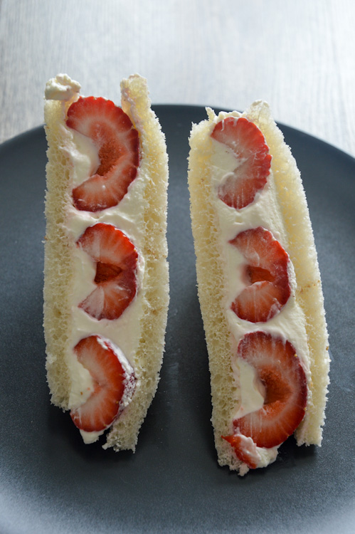 Strawberry sando (Japanese fruit sandwiches) - two pieces standing upright on a black plate